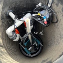 High-quality sump pump system installed in a service pit, featuring durable piping, wiring, and accessories for reliable basement or crawl space water removal, emphasized for professional plumbing services.